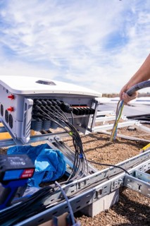 Technician works with cables on an energy converter under a blue sky, PV Assembly. OBI Baumarkt,