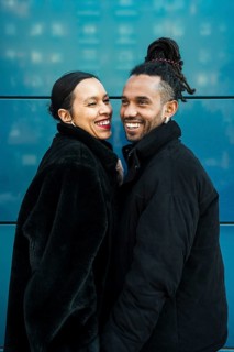 A joyful multicultural couple dressed in stylish winter coats enjoys a happy moment together, set