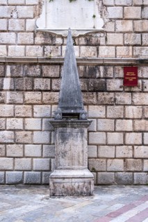 Medieval pillory stands in front of the 17th century clock tower, Old Town Kotor, Montenegro,