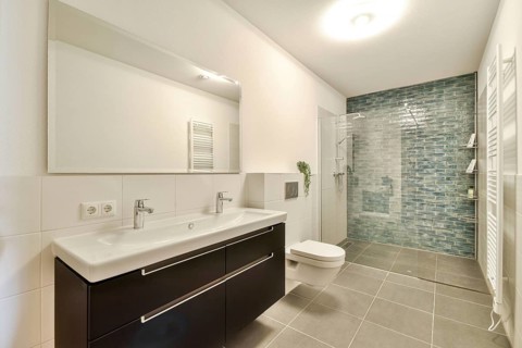 Contemporary bathroom featuring stylish fixtures, a sleek vanity, and a mosaic tile wall that adds