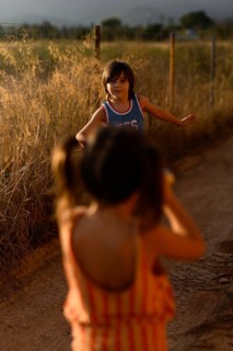 Two children joyfully play on a dirt path in Santa Maria del Cami, Mallorca, surrounded by golden