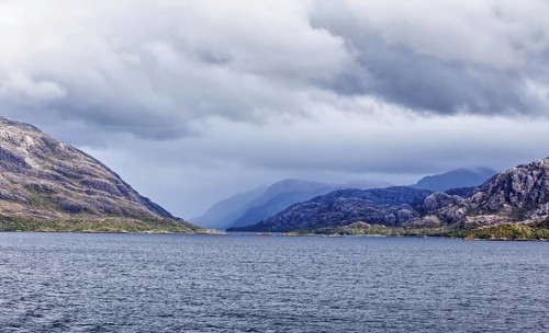 Extensive landscape with mountains and sea under a cloudy sky, coordinates: 51°49'58.83 S, 73°41'30