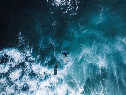 Aerial view of a surf session in Portugal, featuring surfers navigating the vibrant blue waves. The