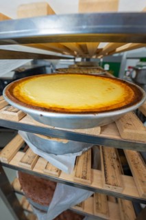 Freshly baked cheesecake in a tray on a wooden shelf in a bakery