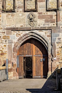 Wooden gate in a robust stone wall with a heraldic coat of arms above it, The gate of Spangenberg