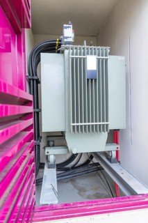 Large transformer in a pink-framed housing with cables, switch cabinet construction, PV system