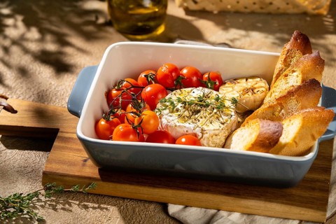 A baked Camembert cheese dish, paired with roasted cherry tomatoes, garlic, and crispy baguette