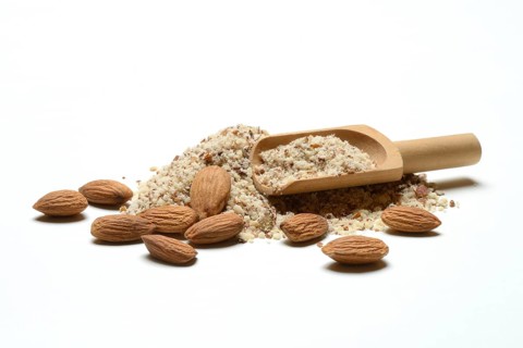 Almonds and ground almonds with wooden scoop, Prunus amygdalus