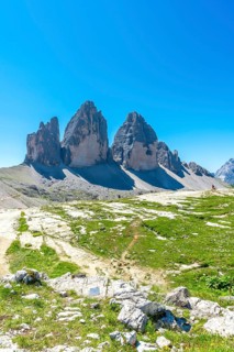 Tourists hiking on the trail leading to tre cime di lavaredo under a blue sky in summer, dolomites,