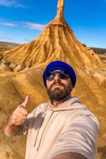 Tourist wearing sunglasses and a blue turban is taking a selfie while gesturing thumbs up in the