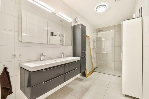 Spacious modern bathroom featuring a large walk-in glass shower, sleek double sink vanity with