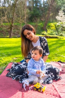 Mother and baby boy enjoying quality time together, playing with toys on a blanket in a sunny park,