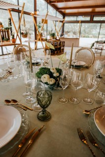 Beautifully set round table with fine glassware, white dinnerware, gold cutlery, and a central
