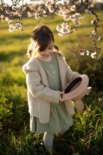 A gentle portrait of a young girl in a cozy sweater and dress, delighting in the surroundings of