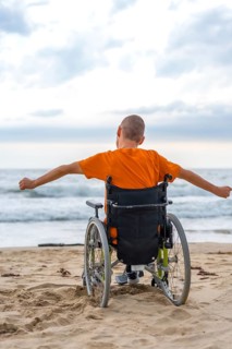 A disabled person on his back in a wheelchair on the beach