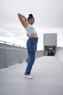 A woman in blue jeans is dancing on a bridge. Concept of freedom and joy, as the woman is fully