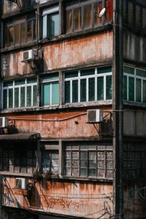 Close-up of an aged building facade featuring barred balconies and windows for security and