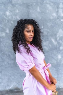 Vertical portrait of a confident latin female model posing with purse and pink attire