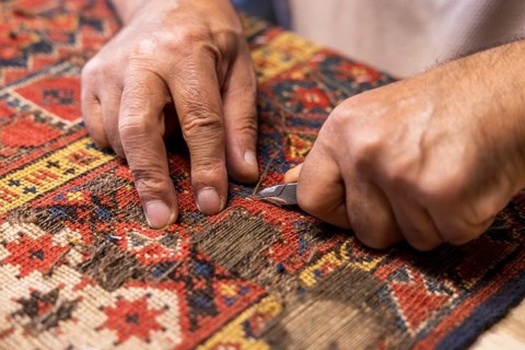 Cropped unrecognizable senior master craftsman from Iran meticulously restores a vibrant,