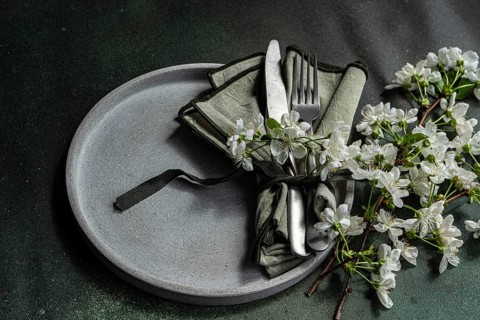 A sophisticated table setting features a gray plate with neatly arranged cutlery and a green
