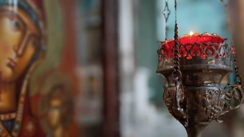 A burning candle in front of an iconic painting in an atmospheric Orthodox church, Georgia