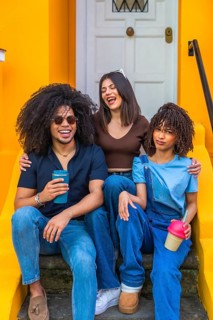 Three young friends are enjoying a relaxing time together, sitting on steps, laughing, and holding