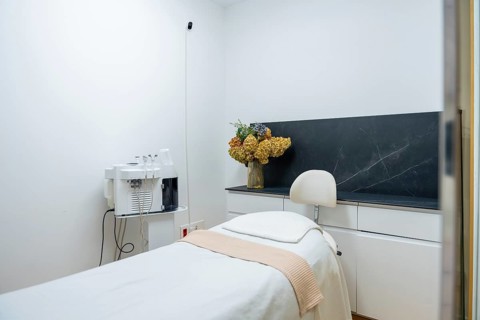 Modern aesthetic clinic interior featuring a clean treatment bed and advanced beauty machine,