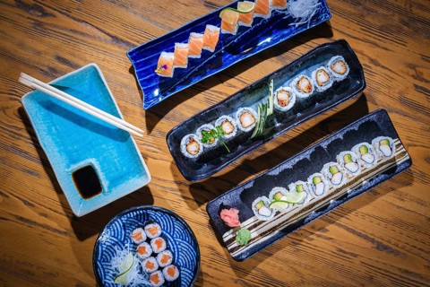 Overhead view of various sushi rolls beautifully arranged on ceramic plates, ready to be savored