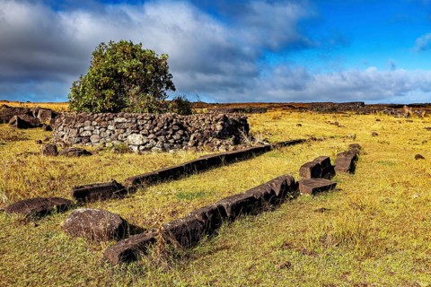 Ancient stone construction on a grassy field under a blue sky, The ruins on Easter Island in the