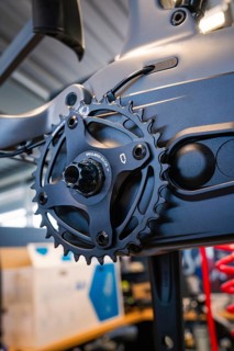 Black chainring on a bicycle frame in a well-lit workshop, Waldbike Manufaktur, bicycle workshop,