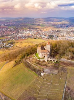 A view of the castle towering majestically over the fields, overlooking tree-lined hills,