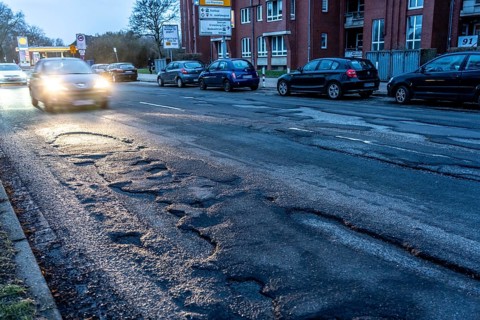 Many large potholes on an inner-city road, Lange Straße in Krefeld-Uerdingen, the heavily