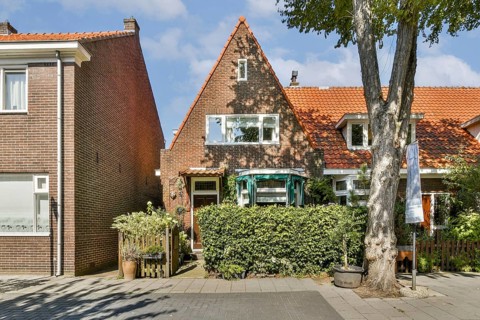 A picturesque house featuring a gabled roof, vibrant greenery, and a welcoming front yard, set