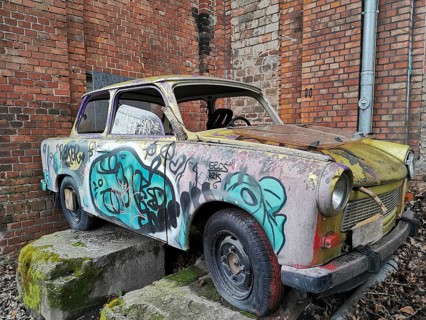 Abandoned old Trabant car with graffiti on a brick wall in a backyard, Berlin
