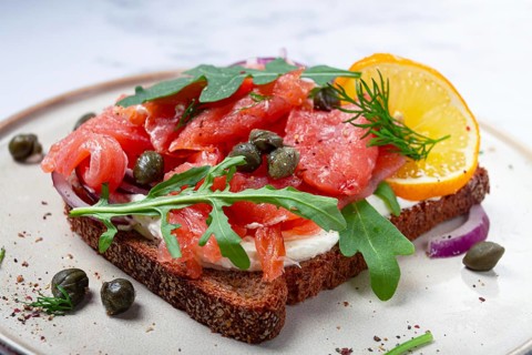 Sandwich with freshly smoked salmon, on black bread, with cottage cheese, with herbs and red