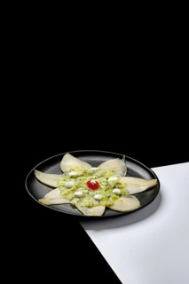 A gourmet dessert featuring fresh kiwi and pear slices arranged elegantly on a black plate The