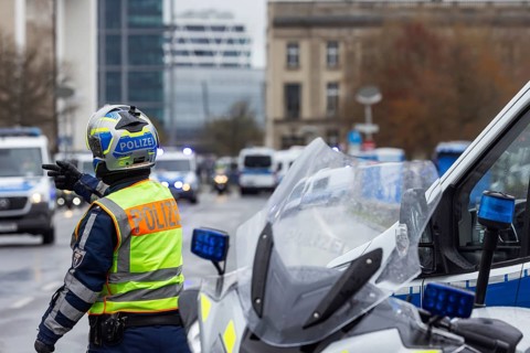Police officers are standing in the rain. Police motorcycles with flashing lights in front of the