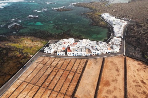 Aerial shot of the vibrant Salares de Orzola in Lanzarote, showcasing the salt pans adjacent to a