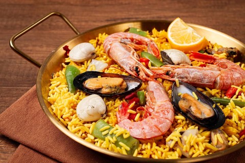 Seafood paella, in a frying pan, on a wooden table, no people