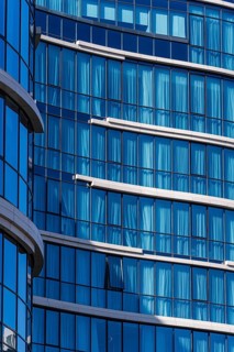 Close-up view of a contemporary building showcasing a reflective blue glass facade, accented by