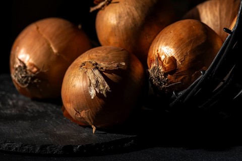 Onions in a basket, lit up in a warm, rustic atmosphere