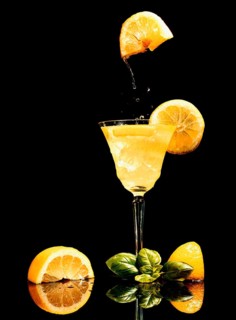 Food photography, lemon floating over glass with lemon juice, cocktail, black background