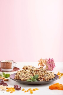 Homemade granola from oat flakes, dates, dried apricots, raisins, nuts in blue ceramic plate with a
