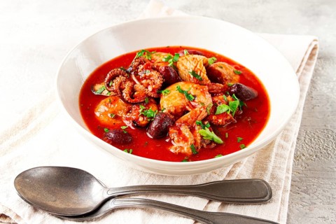 Seafood assortment in tomato sauce, olives, in a white plate