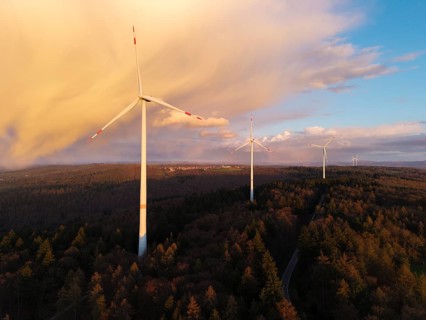 Wind turbines in the forest at dusk, with eye-catching cloud formations in the sky, near
