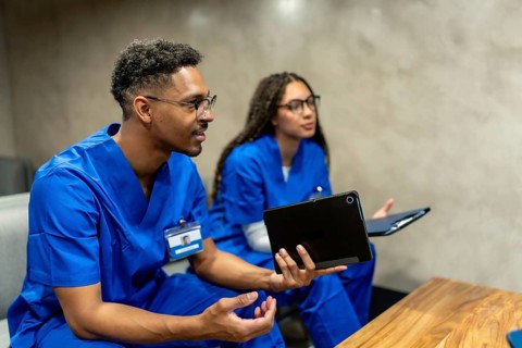 Healthcare professionals in blue scrubs collaborating and discussing patient data, utilizing