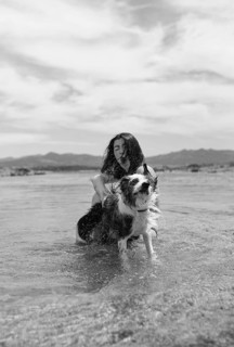 A cheerful black and white scene of a woman playing with her dog in shallow water on a sunny day