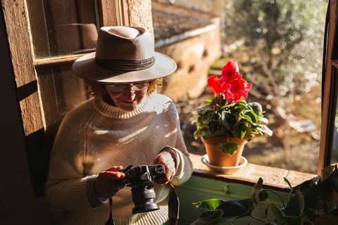 In a serene Barcelona countryside home, a senior woman enjoys the scenic view through a window,