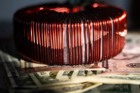 Industrial copper wire coil placed near US dollar bills, symbolizing the link between technology,
