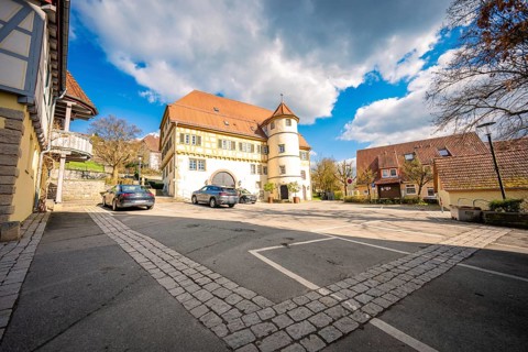 Homestead with paved courtyard and parked cars, blue sky with clouds in the background, Deufringen,